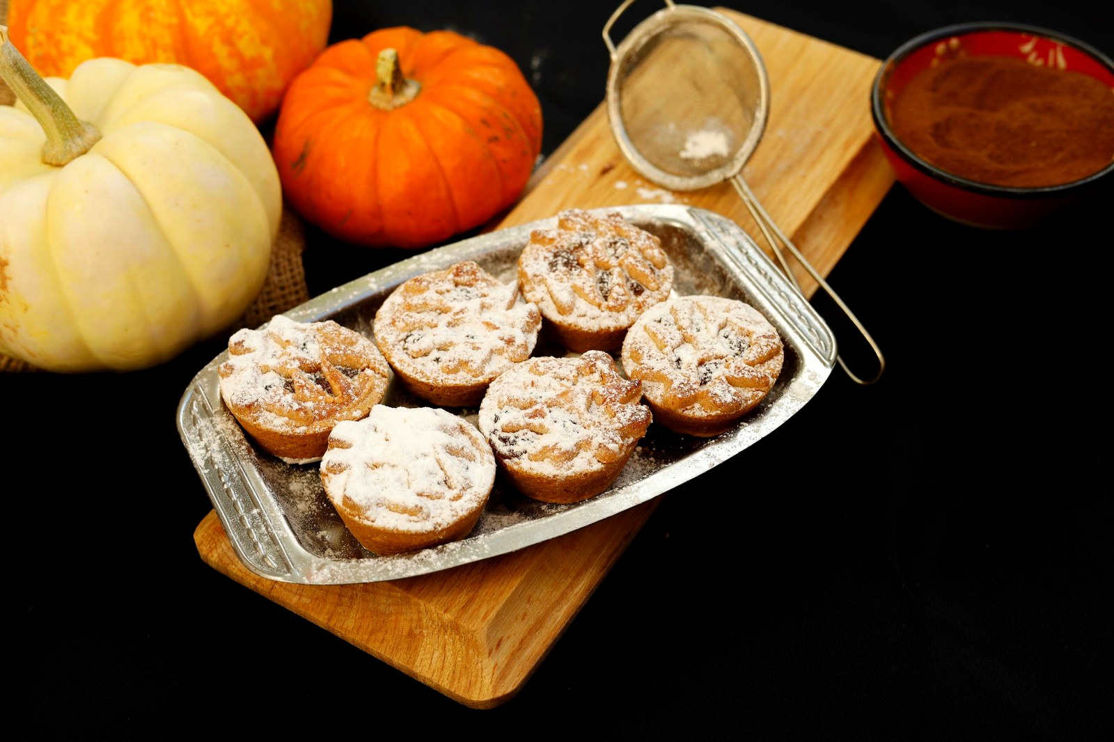 pumpkin spice muffins on a tray with pumpkins and cinnamon